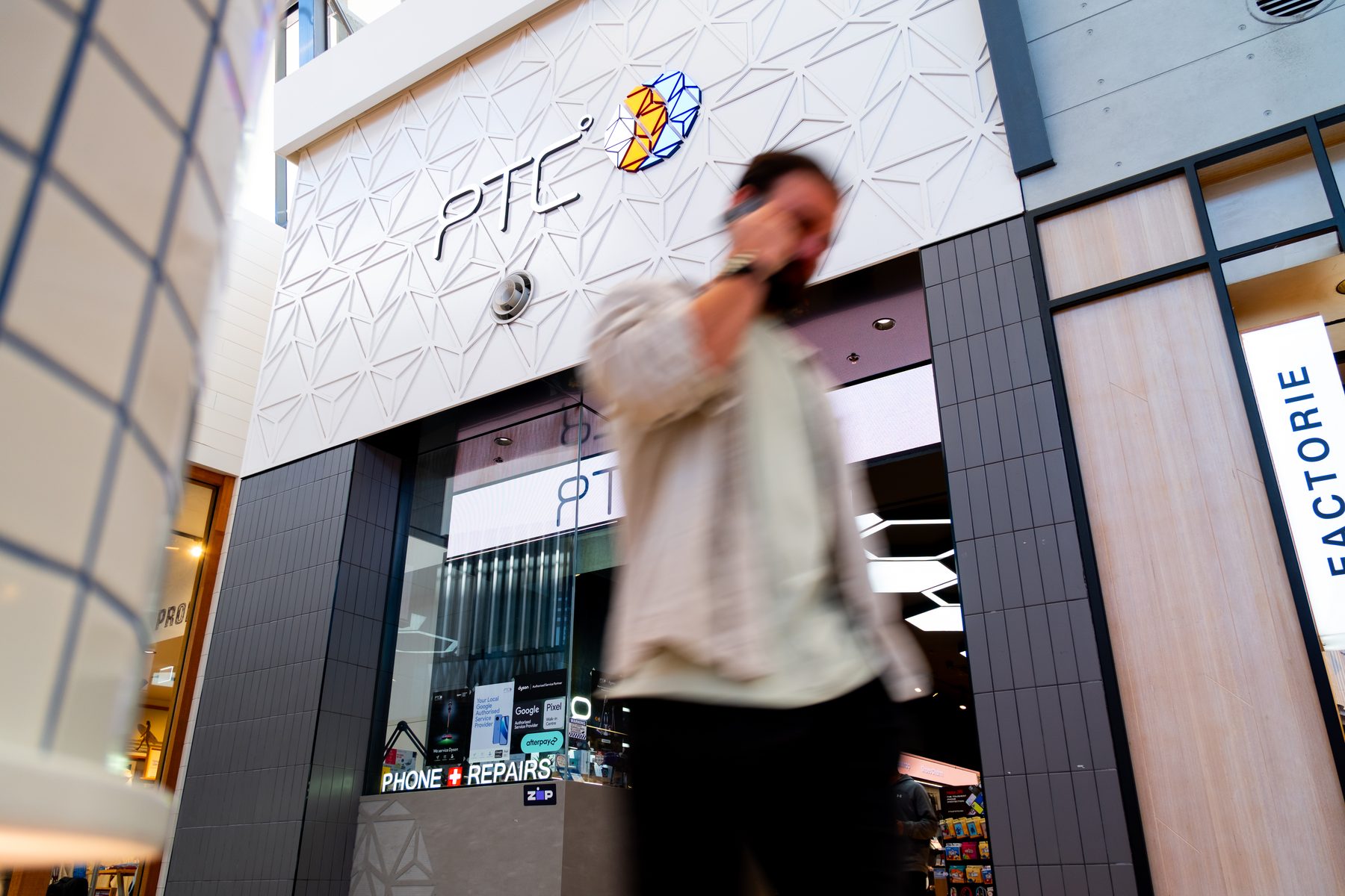 A customer on their phone outside a PTC Phone Tech & Comm store